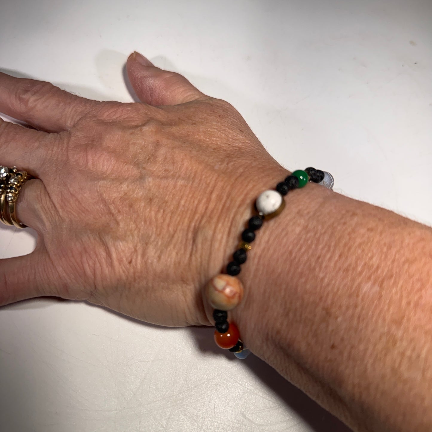 Roccia Roba - Hand wearing a beaded You are the Sun bracelet on a white background