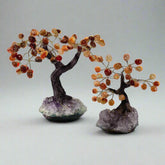 Two gemstone bonsai trees with orange colored branches on amethyst crystal bases.