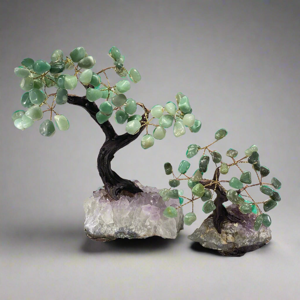 Two gemstone bonsai trees with green quartz leaves, set on amethyst crystal bases with wire trunks and branches.