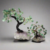 Two gemstone bonsai trees with green quartz leaves, set on amethyst crystal bases with wire trunks and branches.