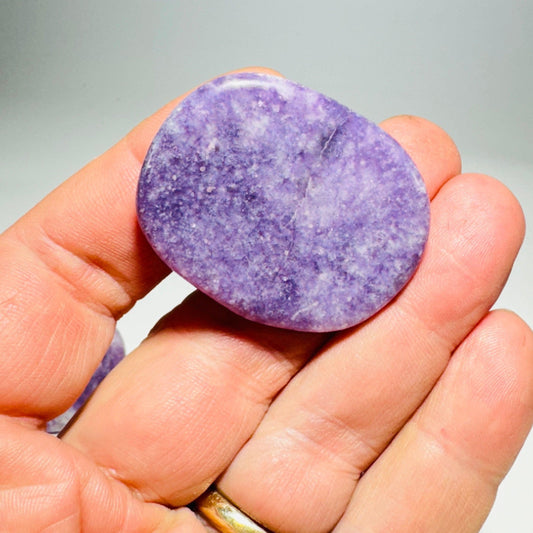 Oval purple lepidolite cabinet knob held in hand, polished stone face