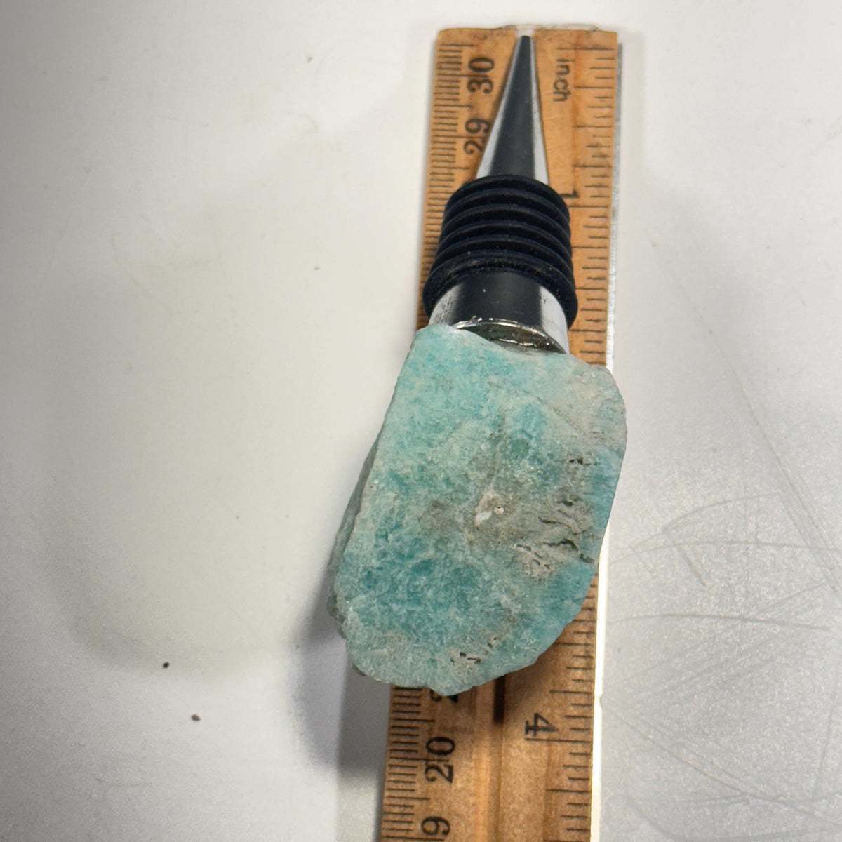 Crystal bottle stopper size comparison with light blue-green stone and ridged black plug