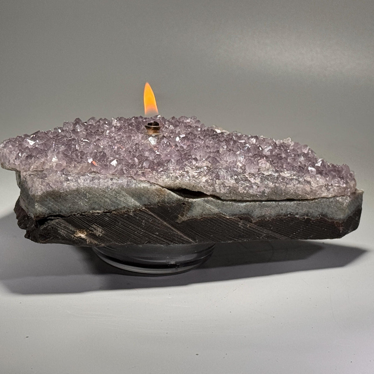 Amethyst geode rock candle with flame and metal wick holder, purple crystal