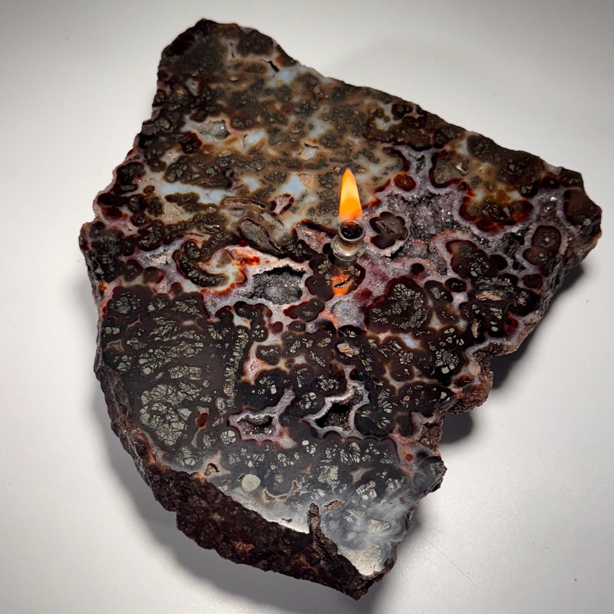 Rock candle flame centered on dark agate stone slab with light speckling