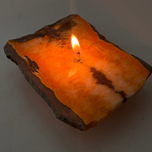 Jasper rock candle with bright orange glow and small flame in clear holder