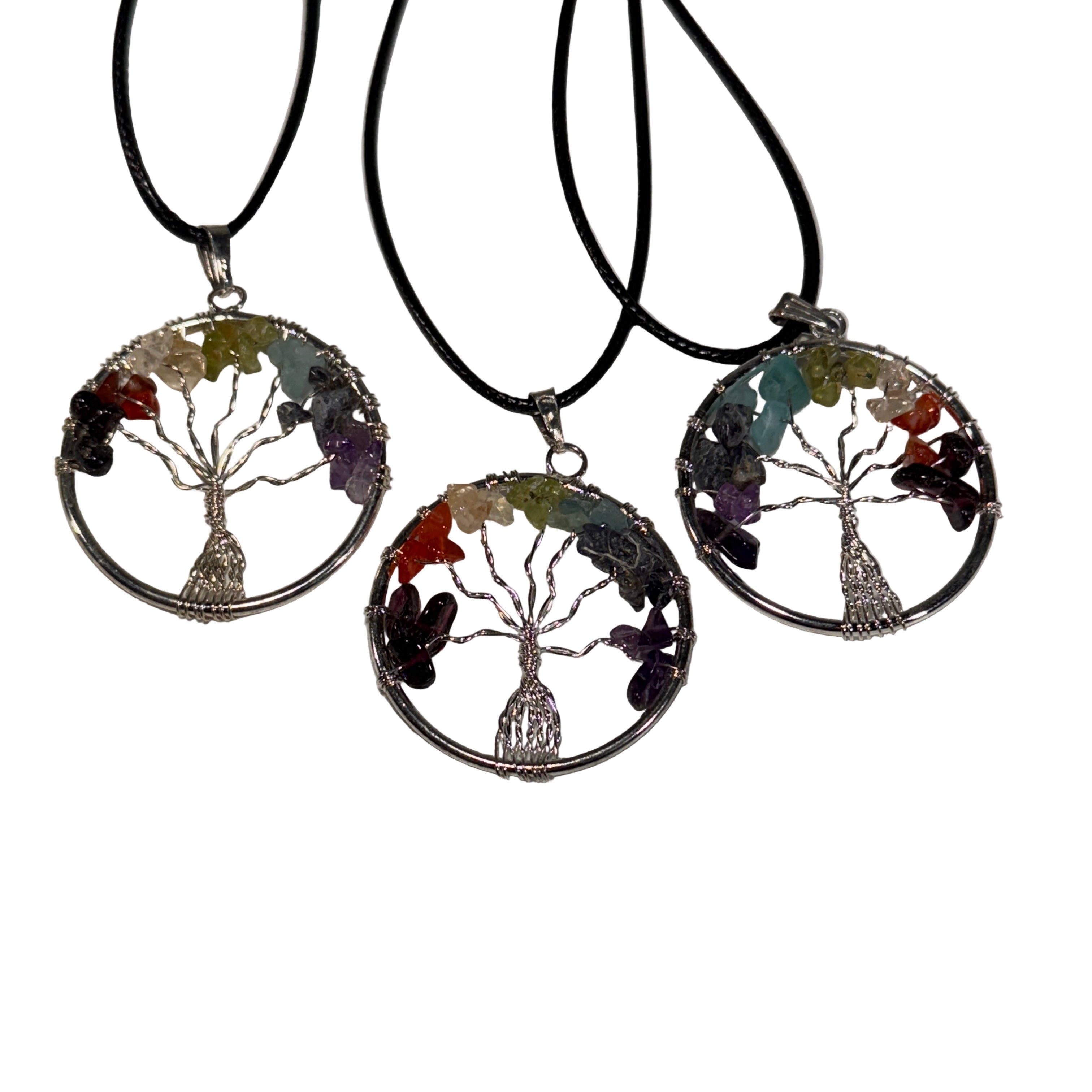 Three tree-shaped pendants with colorful stones on black cords against a white background