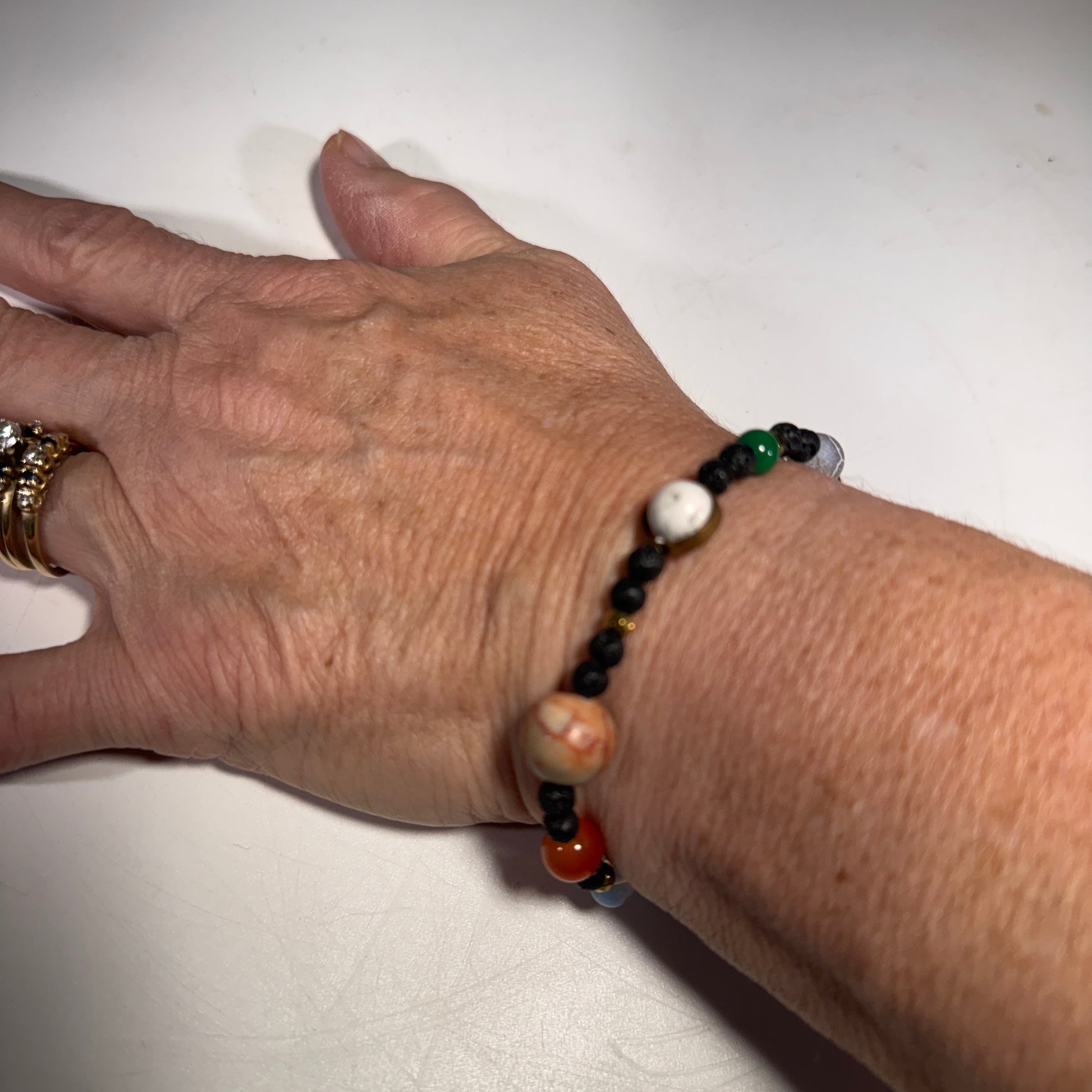 Roccia Roba - Hand wearing a beaded You are the Sun bracelet on a white background