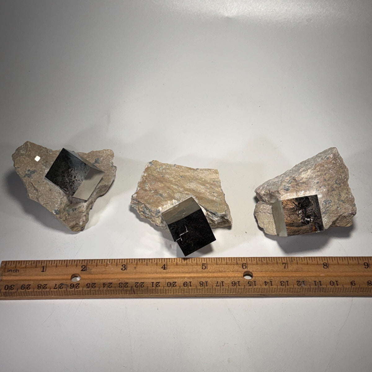 Pyrite crystal in matrix with measuring tape, dark blocky cubes showing