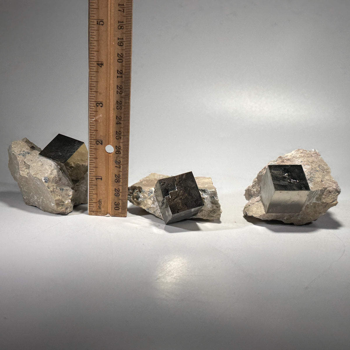 Pyrite crystal in matrix with ruler for scale, dark cube pyrite faces visible