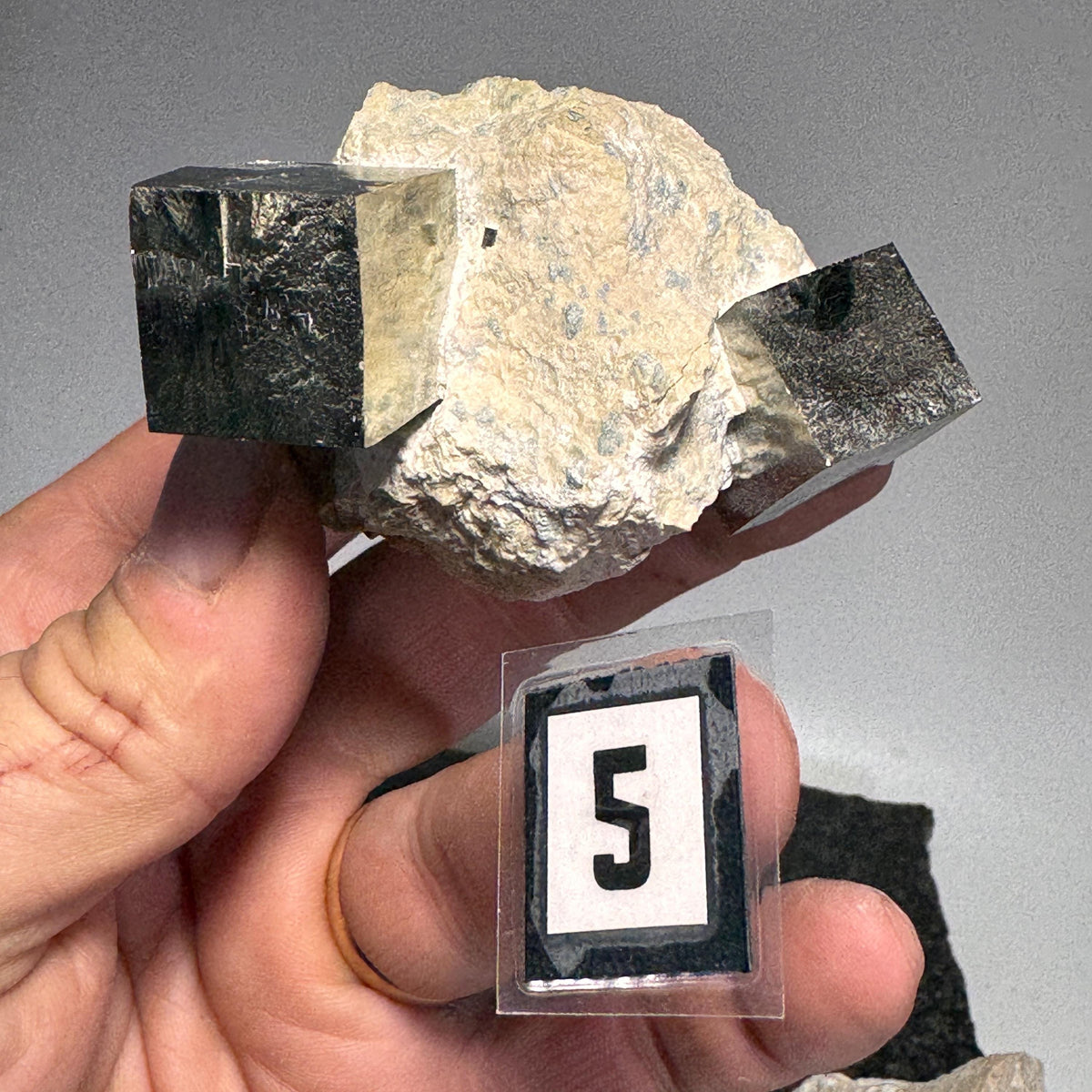 Pyrite cube cluster in tan rock matrix with black metallic cube faces